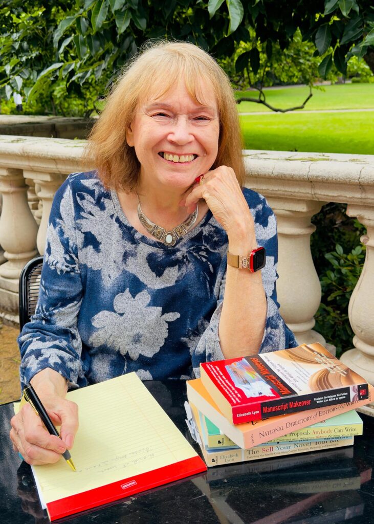 Elizabeth Lyon, author and independent book editor, smiling next to copies of her books